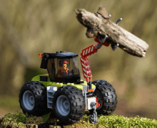 a toy tractor with a crane lifting a log