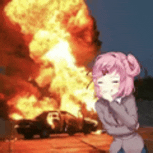 a pink haired anime girl is standing in front of a car on fire .