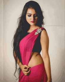 a woman with long hair is wearing a pink saree and a black crop top