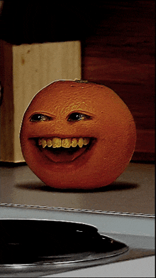 an orange with a smiley face and a knife block in the background