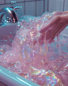 a person washing their hands in a bathtub filled with pink water