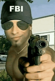 a shirtless man wearing a fbi hat and sunglasses is pointing a gun at the camera .