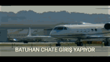 a private jet is parked on a runway with the words batuhan chate giris yapiyor