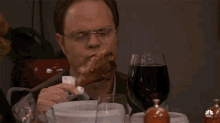 a man is eating a piece of meat at a table with wine glasses