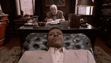 a man in a suit is laying in a chair in front of a desk