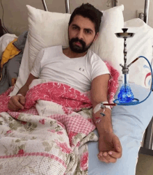 a man laying in a hospital bed with a hookah on his arm