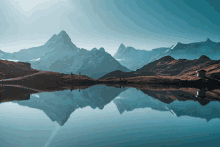 a lake surrounded by snowy mountains and a small house