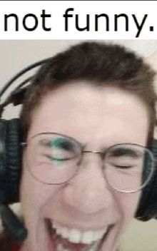 a man wearing headphones and glasses is laughing .