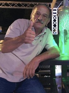 a man gives a thumbs up in front of a bottle of belvedere vodka