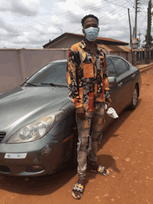 a man wearing a face mask is standing in front of a car