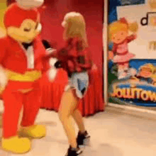 a girl is dancing with a jollibee mascot in a store .