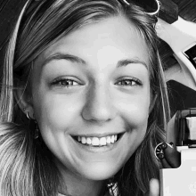 a woman is smiling in a black and white photo while holding a toy car .