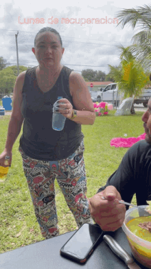 a woman standing next to a man holding a bottle of water with the words lunes de recuperacion written above her