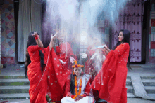 a woman in a white dress is surrounded by other women in red