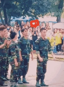 a group of soldiers are standing in front of a crowd with a red heart shaped speech bubble that says i love you