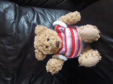 a teddy bear is wearing a striped sweater