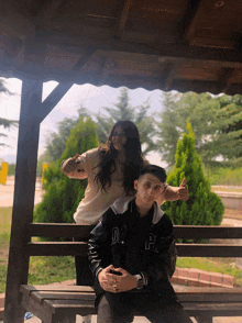 a girl sitting on a bench next to a boy wearing a jacket that says o.