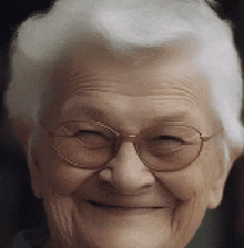 a close up of an older woman wearing glasses and smiling