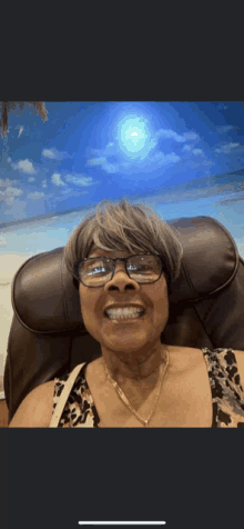 a woman wearing glasses is smiling in front of a beach background