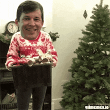 a man wearing a merry christmas sweater is holding a basket of candy canes in front of a christmas tree