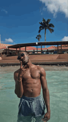 a shirtless man is standing in the water giving a peace sign