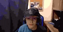 a young boy wearing headphones and a baseball cap is sitting in a chair in a room .