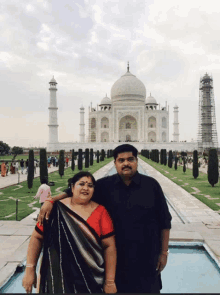 a man and a woman pose in front of the taj mahal in india