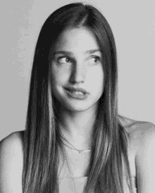 a black and white photo of a woman with long hair and a necklace that says ' i love you ' on it