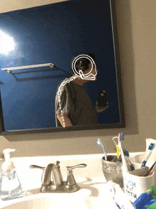 a person taking a selfie in front of a mirror with a drawing of their head on it