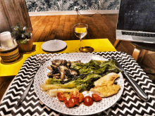 a plate of food on a table with a laptop and a glass of wine