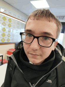 a young boy wearing glasses and a trespass jacket