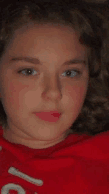 a close up of a young girl 's face wearing a red shirt with the number 1 on it .