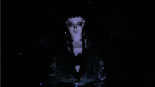 a woman in a black jacket is standing in the dark