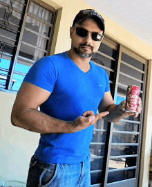 a man in a blue shirt holds a can of skol beer