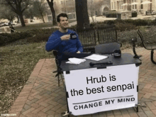 a man is sitting at a table with a sign that says hrub is the best senpai