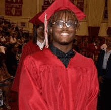 a man wearing a red graduation cap and gown is smiling .