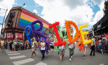 a group of people carrying balloons that spell out pride