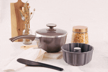 a pot with a lid sits on a table next to a pan