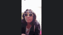 a woman wearing sunglasses and a jacket is making a face