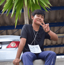 a boy sitting on a wall with a sign around his neck that says ' stv ' on it