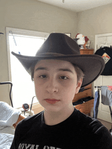 a young boy wearing a cowboy hat and a black shirt that says royal oak