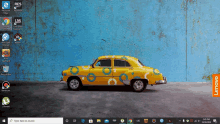 a yellow car with blue circles painted on it is on a lenovo computer