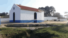 a small white building with a red roof sits in the middle of a field