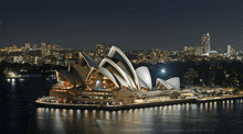 the sydney opera house is lit up at night with the city in the background