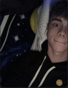 a young man is laying on a bed with a pillow and a blanket with a moon and stars on it