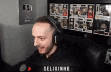 a man wearing headphones is sitting in front of a shelf full of pop figures .