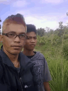 two young men are standing next to each other in a field .