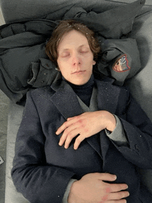 a man laying on a couch with his eyes closed and a jacket that says ' boston bruins ' on the back