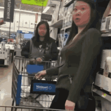 two women are standing next to each other in a grocery store pushing a shopping cart .