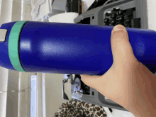 a person is holding a blue bottle with a green band